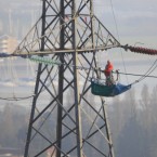 A lone engineer works in a gondola attached to high voltage power lines high above the ground in Hampshire, England. Pic:Chris Ison/PA Wire