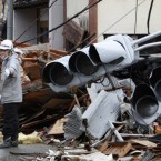 A construction worker controls the traffic at a devastated area in Kesennuma, northern Japan, while traffic lights destroyed by the tsunami lie behind him. (AP Photo/Shizuo Kambayashi)