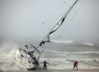 One of two people rescued from a sailboat, right, uses a line to make their way onto the beach on Willoughby Spit in Norfolk, Virgina yesterday.