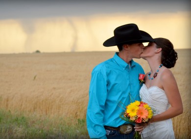 Caleb & Candra Pence pose for a wedding photo as a tornado swirls in the background