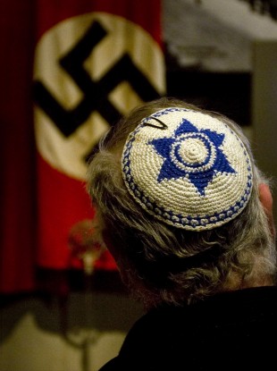 A Jewish man looks at exhibit showing the Nazi flag, during a visit at Yad Vashem Holocaust Memorial in Jerusalem Sunday, April 11, 2010