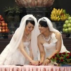 You Ya-ting, left, and her partner Huang Mei-yu stamp their names in front of a statue of Buddha in the prayer hall as they are married in the first gay Taiwan Buddhist ceremonial wedding in Taoyuan, Taiwan. The country still does not legally recognise same sex marriage. (AP Photo/Wally Santana)