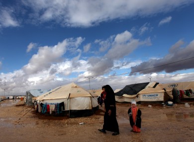 A Syrian refugee woman walks with her two kids at Zaatari Syrian refugee camp, near the Syrian border in Mafraq, Jordan.