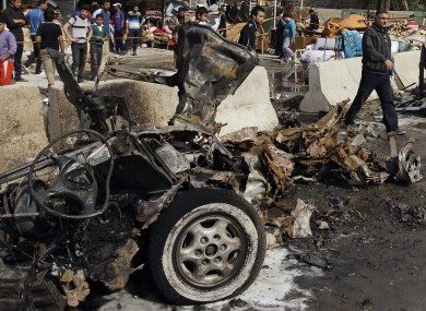 Iraqis inspect the scene of a car bomb attack in the Ameen neighborhood in eastern Baghdad, Iraq