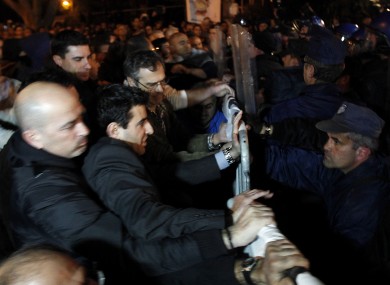 Employees of Laiki Bank, left, push barriers as riot police try to stop them during an anti-bailout protest outside the Cypriot parliament in Nicosia, Cyprus