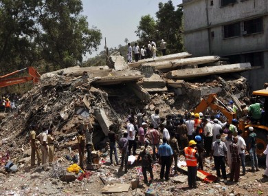 People gather around a heap of debris at the site of a building collapsed as a rescue operation continues.