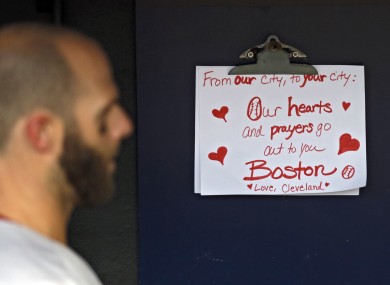 Boston Red Sox's Dustin Pedroia walks past a condolence sign in the dugout .