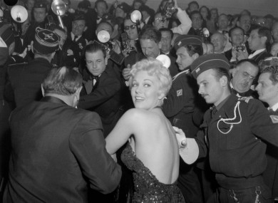 Kim Novak is hustled through the crowd of media to attend an evening performance at the Cannes Film Festival in 1956