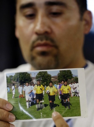 Jose Lopez points to an undated photo of Ricardo Portillo, centre, his brother-in-law.
